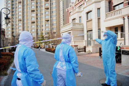 Varios trabajadores visitan a una familia en cuarentena en Qingdao, provincia de Shandong, China. EFE/EPA/YU FANGPING/Archivo 